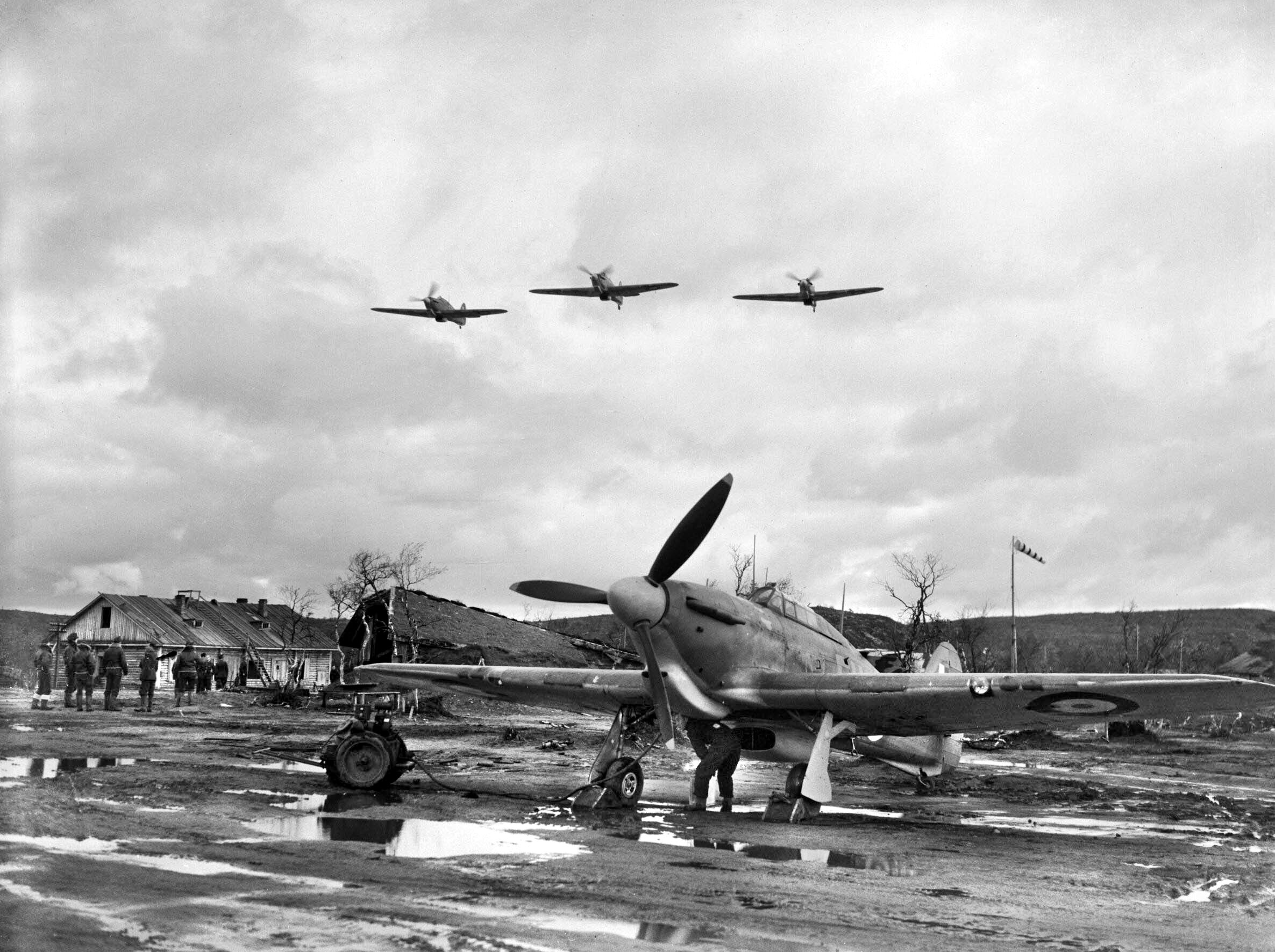 A trio of Hurricane Mk IIB fighters from No. 81 Squadron RAF fly over the Vaenga airfield in northern Russia, waterlogged from rains and probably melting snow as well. Approximately 2,700 RAF personnel from 151 Wing sailed from the anchorage at Scapa Flow in the Orkney Islands of Scotland for Russia on August 17, 1941. Fifteen Hurricanes, loaded in crates, were aboard ship with them.