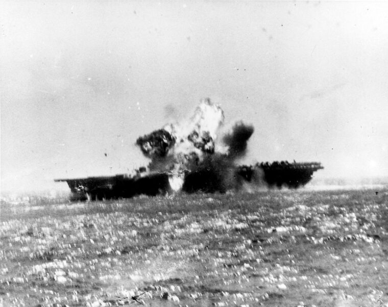 Imperial Japanese Lt. Yoshinori Yamaguchi’s special attack D4Y3 Model 33 “Judy” dive bomber, burning after being hit by antiaircraft fire, seconds before it hit the Essex. INSET: This photograph from the USS Ticonderoga shows the explosion aboard the carrier USS Essex after Yamaguchi’s kamikaze attack hit the flight deck just before 1 p.m. on November 25, 1944, off the coast of Luzon in the Philippines. 