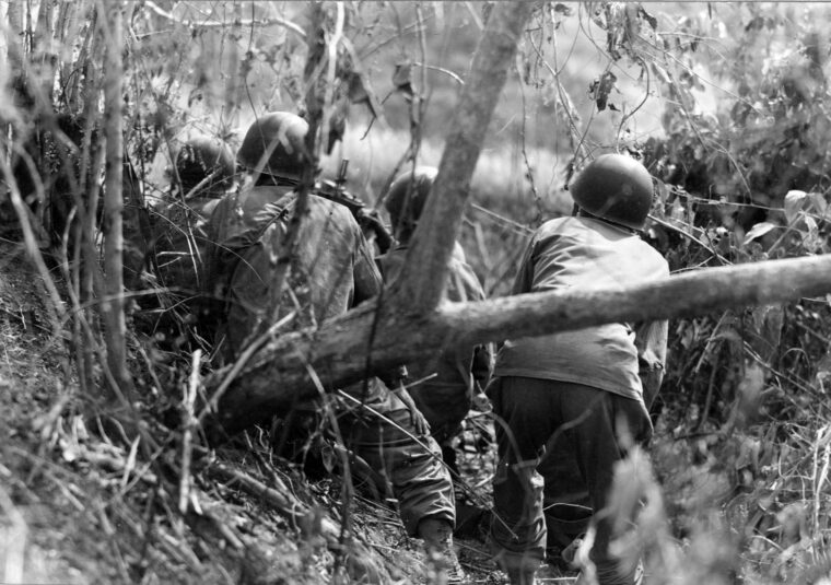 On January 14, 1945, soldiers from D Company, 1st Battalion, of the 158th Regimental Combat Team, fire on a Japanese sniper near the village of Damortis along the Lingayen Gulf of Luzon, Philippines.
