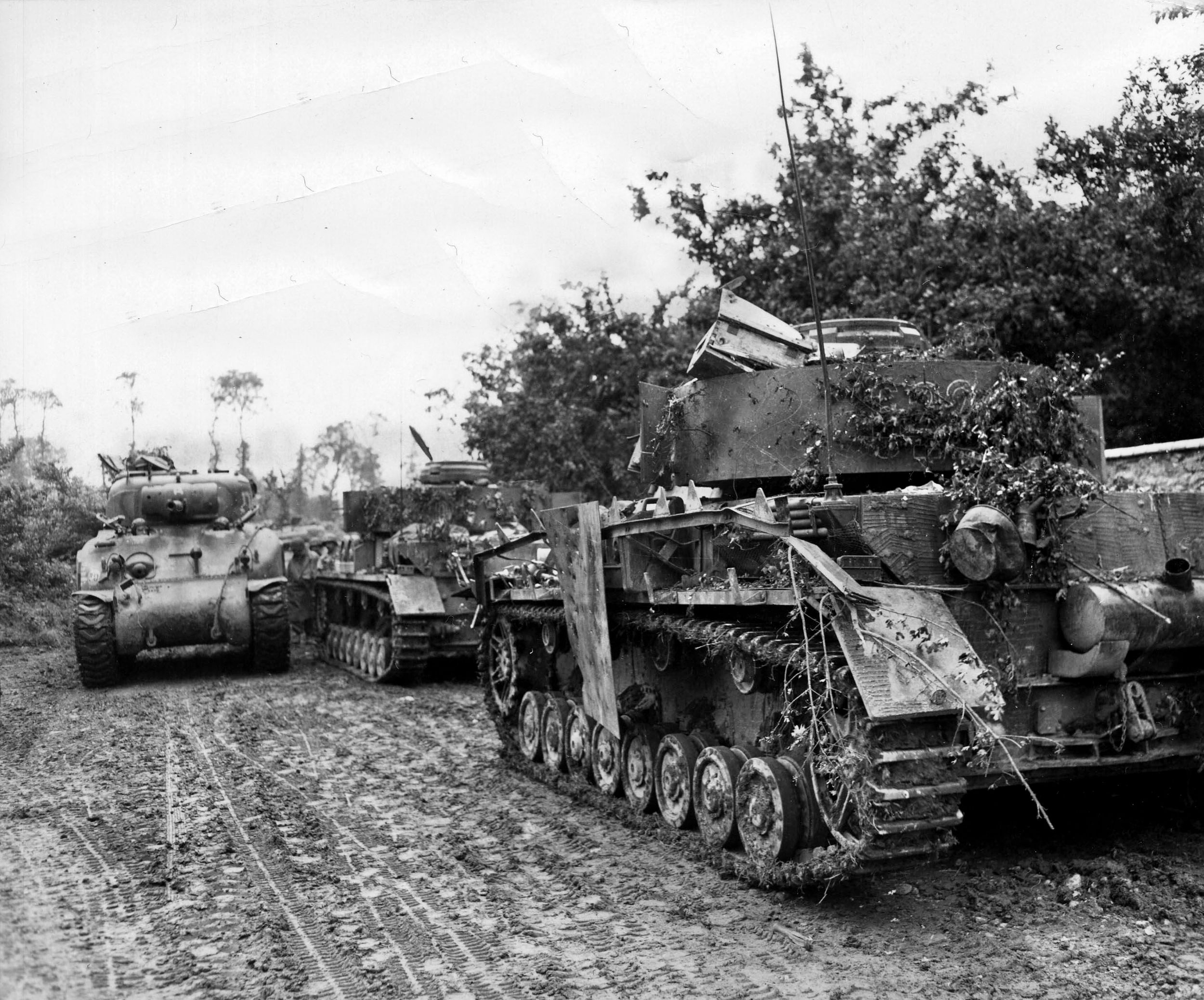U.S. Sherman tanks move past destroyed German Mark IV panzers as the 30th Infantry Division moves on St. Lo. on July 9, 1944. By July 26th, with the help of carpet bombing during Operation Cobra, the Americans were able to break through and continue toward Berlin. 