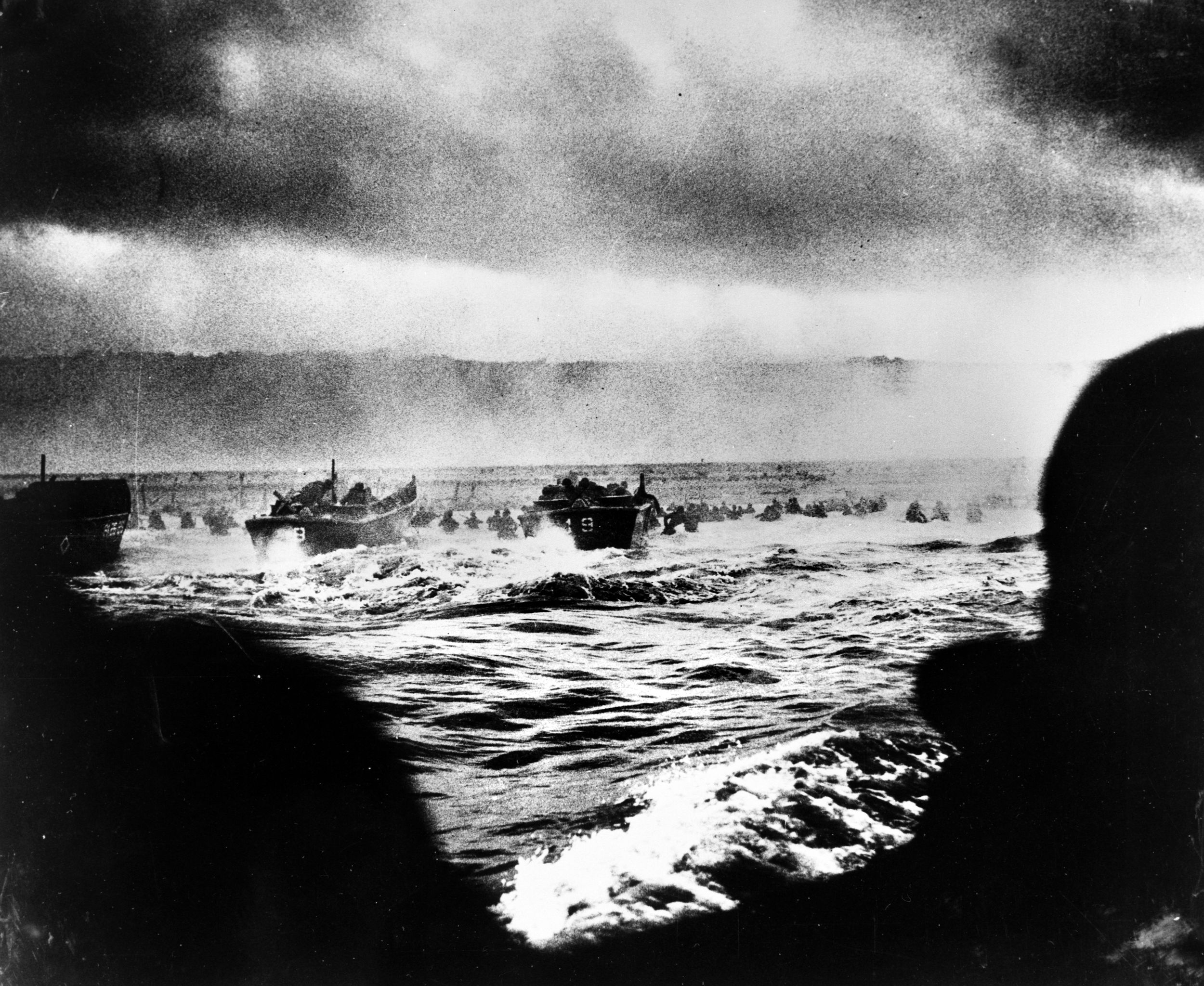 Landing craft approaching Omaha Beach on the coast of Normandy in the opening minutes of D-Day. After the craft carrying Roy Stevens sank 500 yards offshore, he managed to shed his gear and stay afloat for 2.5 hours before he was picked up. Back on Omaha on June 11, he found his brother Ray’s grave and dog tags.