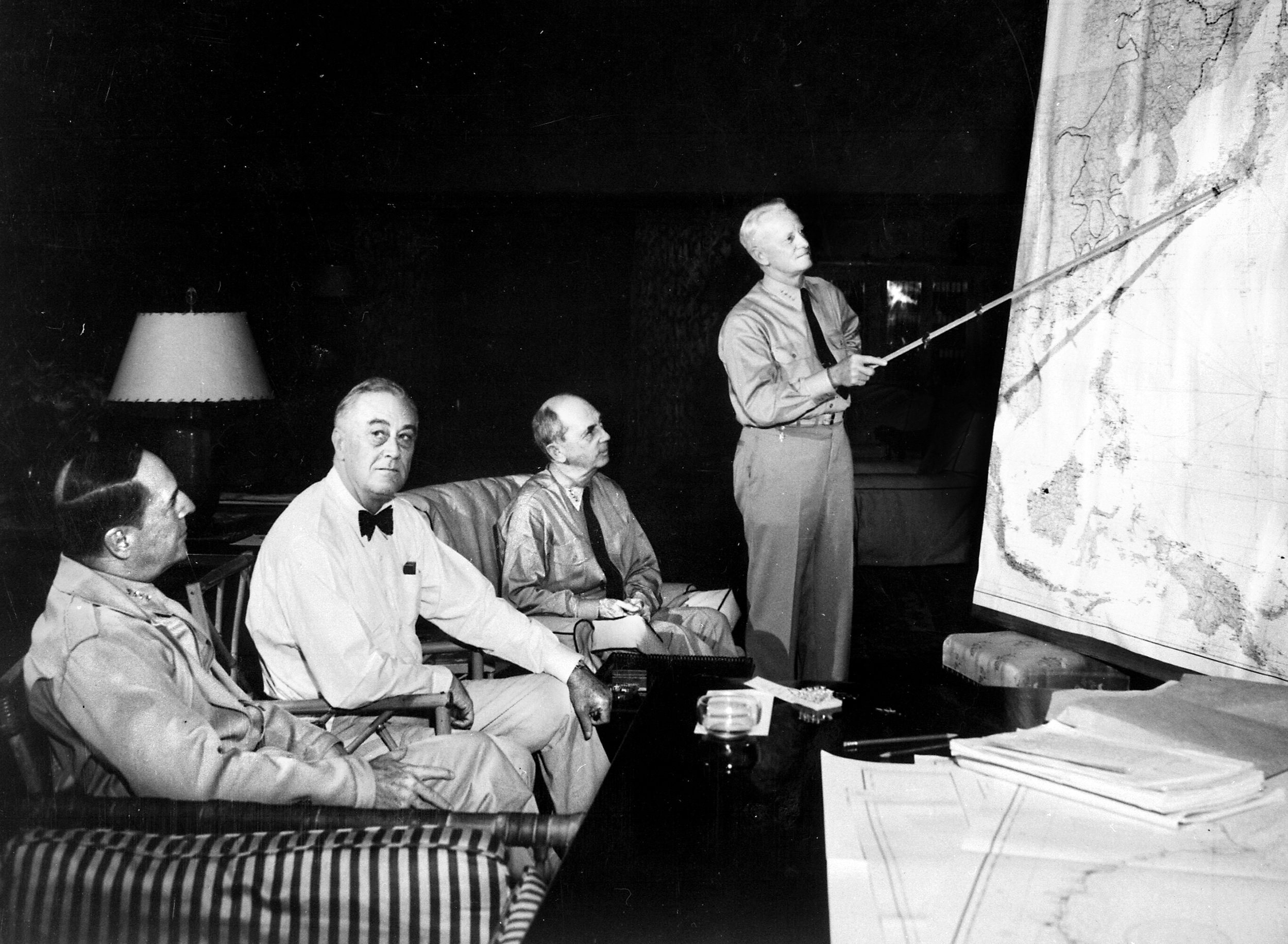 From left are General Douglas MacArthur, President Franklin D. Roosevelt and Admiral William Leahy being briefed by Admiral Chester Nimitz, who directs their attention to a map of the Pacific Theater, during a conference in Hawaii in January 1944. 