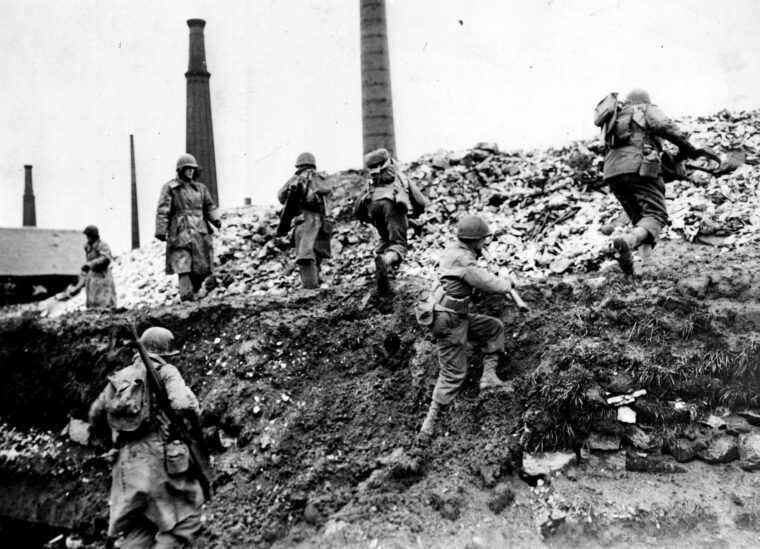 Under heavy fire, soldiers from the 35th Infantry Division scramble up a bank during the grueling house-to-house combat in Sarreguemines, France, in late 1944.