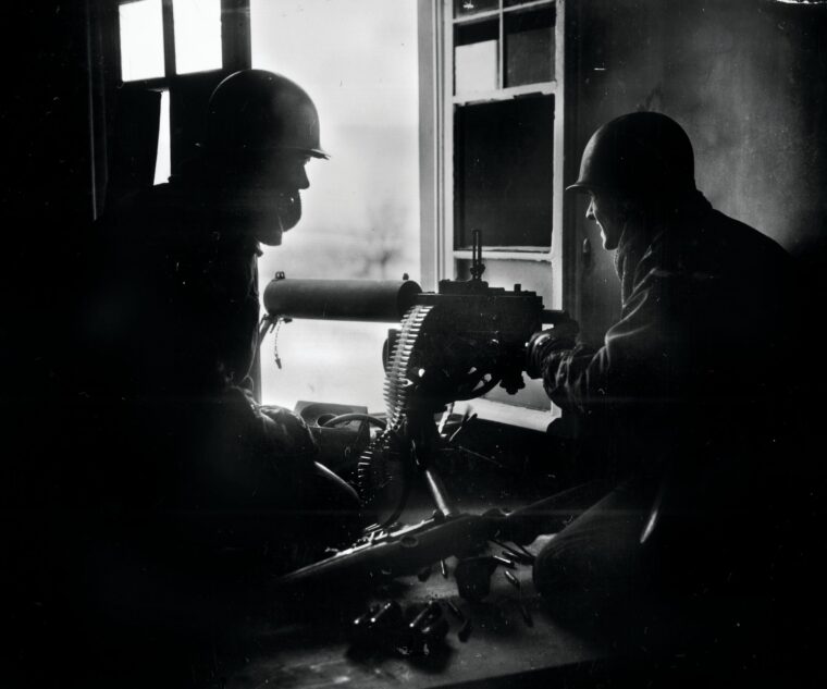 GIs fire a water-cooled M1917 Browning machine gun from the window of a house during the Battle of the Bulge in December 1944. The 3rd Battalion, 110th Infantry Regiment, delayed the Germans for a critical 36 hours at Hosingen, Luxembourg.