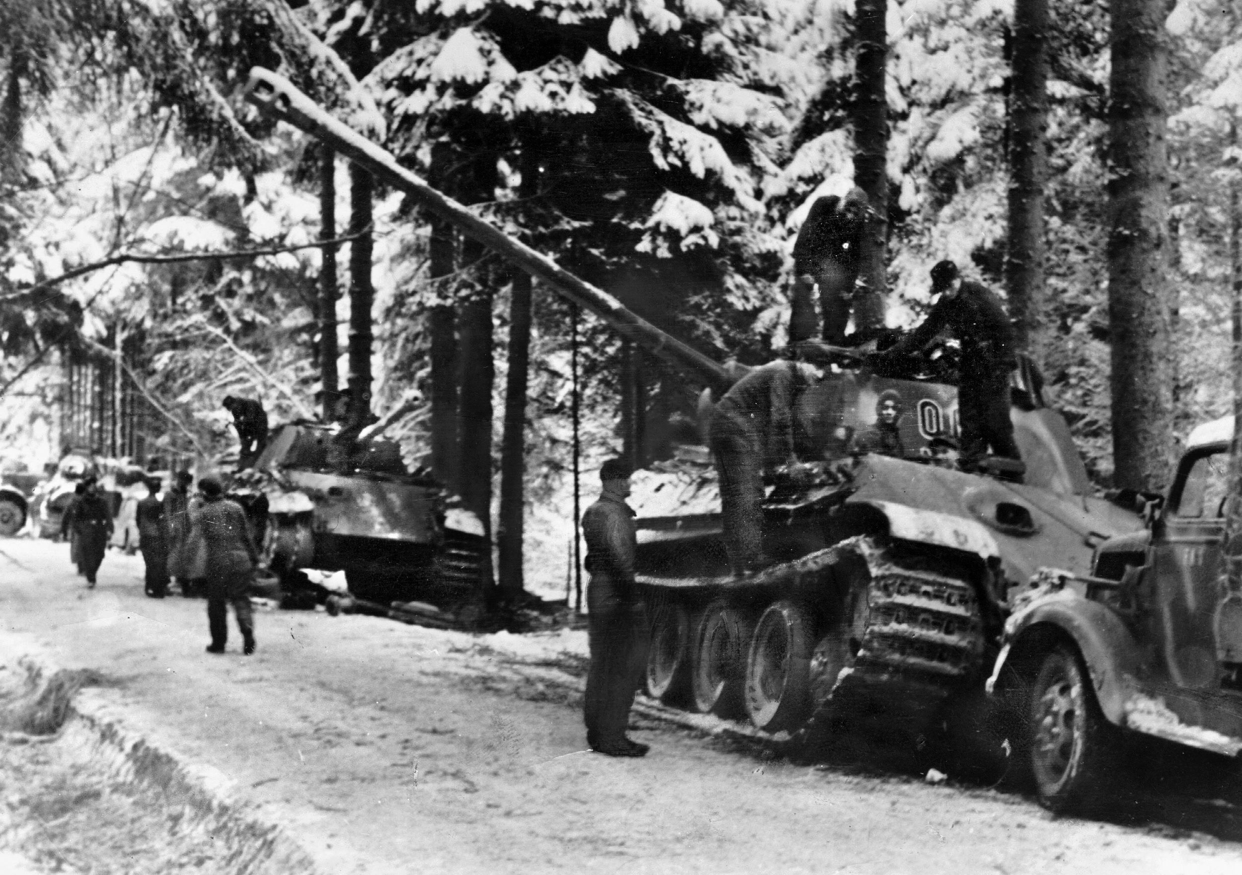German tanks and other vehicles parked on a snowy road during the opening of the Ardennes Offensive of December 1944. The German plan to bypass Allied strongpoints on their way to the Clerf River, and eventually Bastogne, was held up by stiff American resistance at the village of Hosingen on “Skyline Drive.” The need to move heavy equipment and supplies along the road forced the 901st Panzergrenadier Regiment and the tanks of Panzer Lehr Division to commit to the fight.