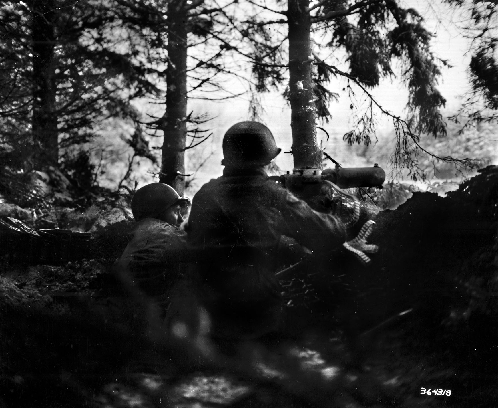 GIs man a Browning .30-caliber M1917A1 water-cooled machine gun in the rugged Ardennes forest during the winter of 1944. These heavy-hitting crews, who often mixed alcohol or antifreeze into their cooling water to keep the guns from freezing, were the backbone of the Allied “Ghost Front” in Luxembourg—where units like the 110th Infantry Regiment, outnumbered 10-1 at Hosingen—were tasked with holding vital ridgelines against the sudden surge of the German Ardennes Offensive.