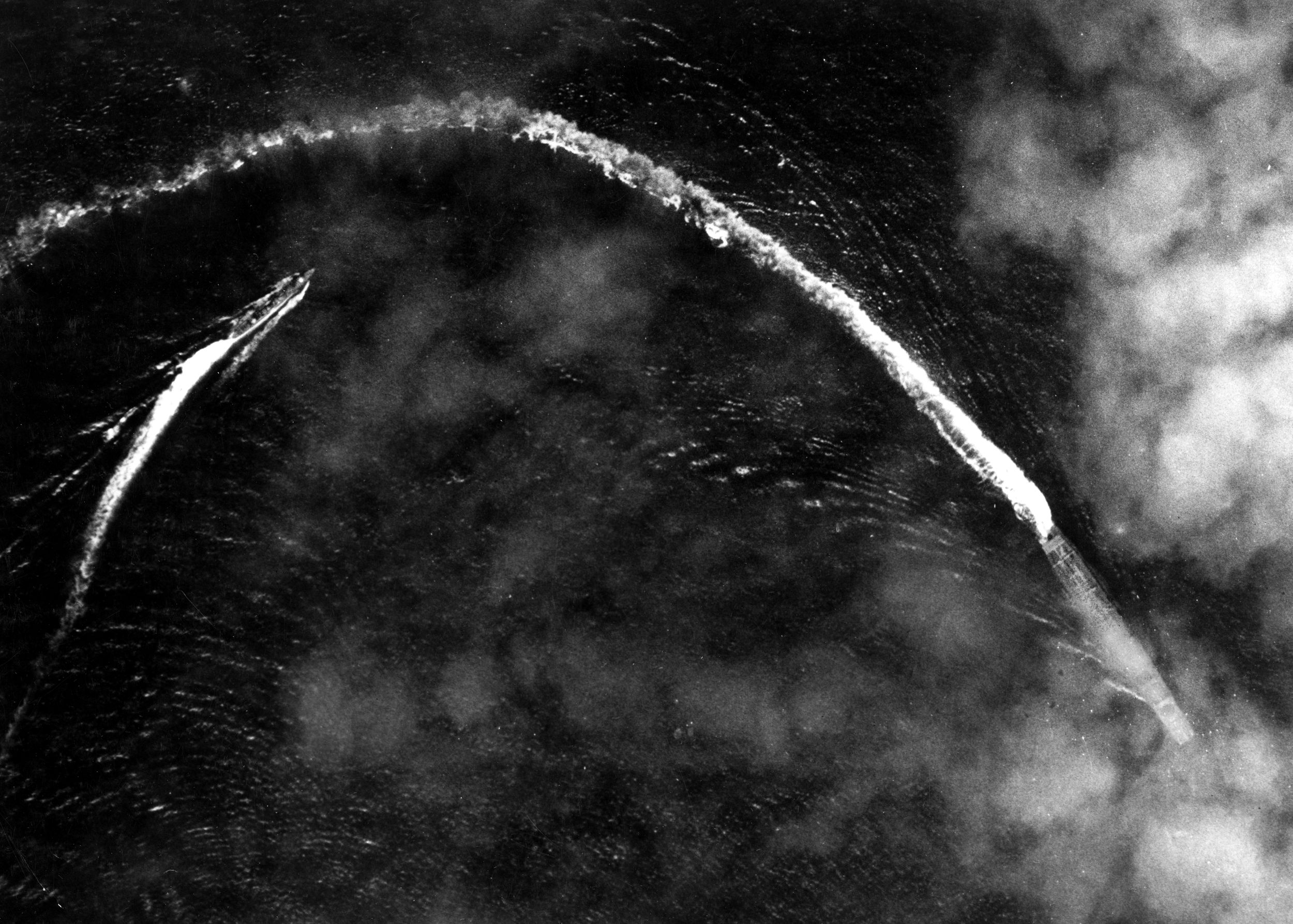 Framed by thin clouds, the Japanese aircraft carrier Akagi and an escorting destroyer carve sharp white wakes as they take violent evasive action to avoid high-altitude bombs dropped by USAAF B-17s flying from Midway, shortly after 8 a.m. on June 4, 1942. The Japanese ships survived several near-misses, but were not so lucky once Navy dive-bombers arrived later that morning.