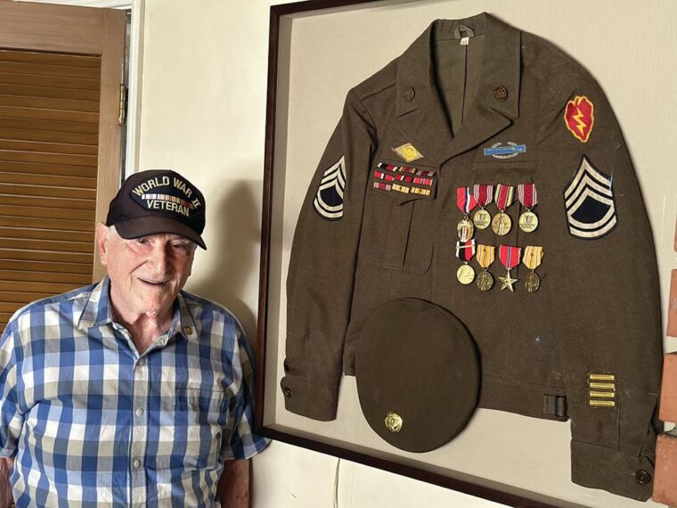 Joe “Peppy” Sciarra next to his U.S. Army service coat with the decorations he earned in the Pacific. A mortarman with the 27th Infantry Regiment, Sciarra fought in the jungles of Luzon, Philippines, where he earned a Bronze Star for his gallantry, leadership, and unyielding endurance under fire during the grueling drive to clear the fiercely defended Balete Pass.