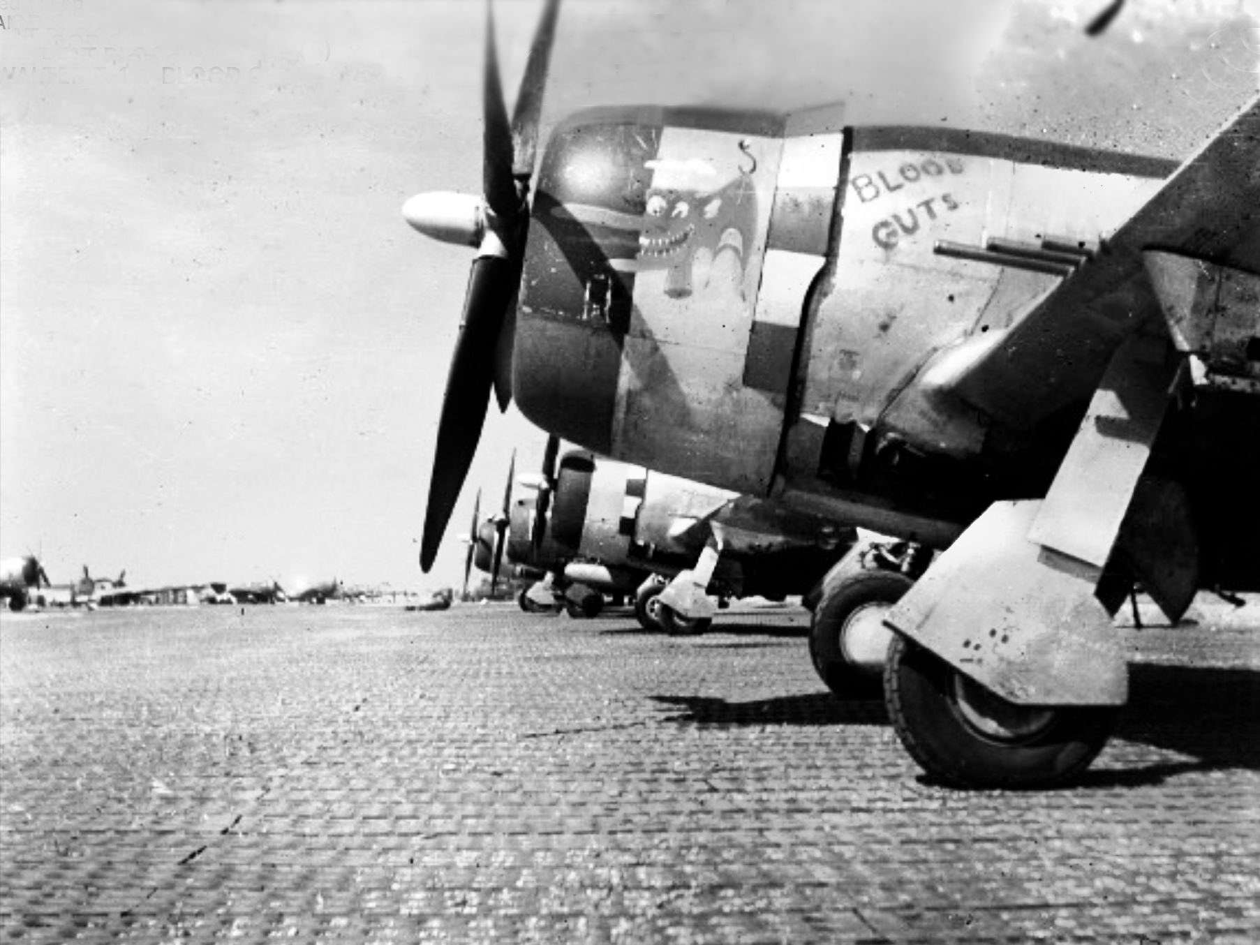 Lieutenant Walter Donovan’s Blood & Guts leads a line of Republic P-47 Thunderbolts belonging to the 510th Fighter Squadron warming up at Advanced Landing Ground A-8 (ALG A-8) in Picauville, France, during the summer of 1944. The squadron moved to this airstrip a few weeks after D-Day, which radically compressed their response times to deliver devastating, low-level close air support to American ground forces driving through the hedgerows.