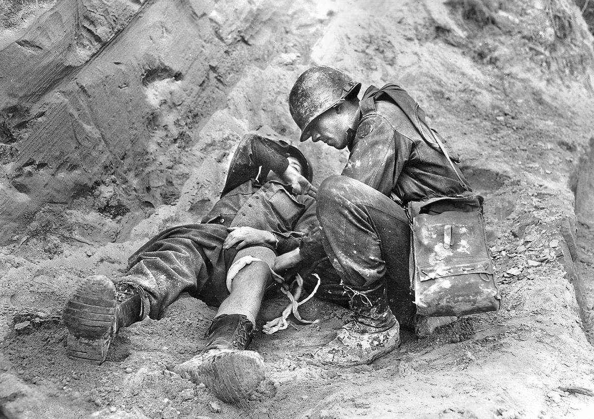 A wounded soldier from the 85th Division receives medical attention from an Army Corpsman.