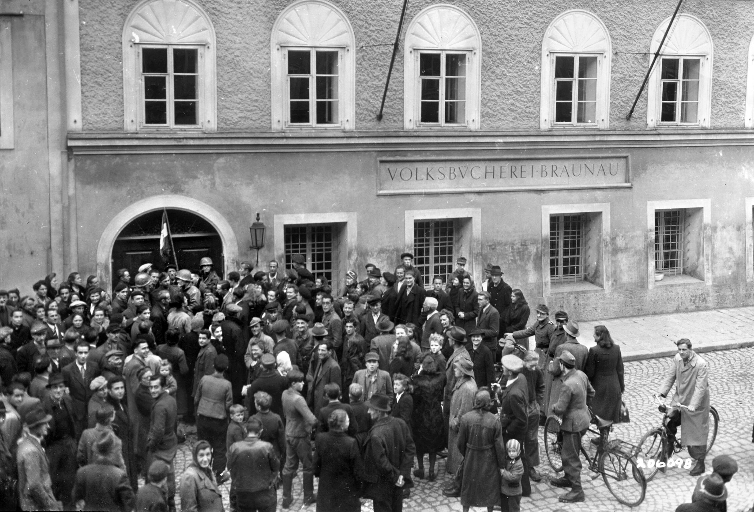 Smiling local citizens guide soldiers from the 67th Armored Infantry Battalion toward the entrance of Adolf Hitler’s birthplace, a three-story former boarding house in Braunau am Inn, Austria. Following the town’s capture in May 1945, curious residents frequently directed advancing GIs to the building where the Nazi dictator was born in 1889.