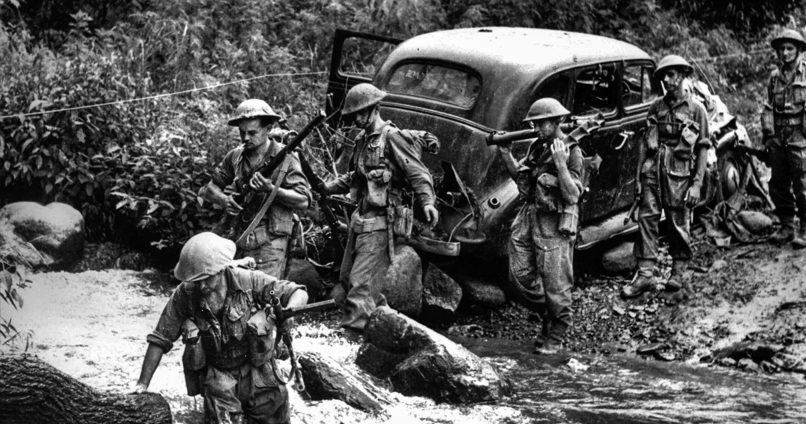 A British corporal leads his squad through a raging torrent of water near Kohima during the fighting on the Assam frontier. Monsoon rains routinely transformed mountain streams into impassable rivers.