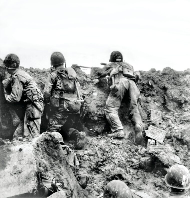 In one of the very few surviving images depicting U.S. troops under actual combat conditions during the early hours of the Normandy invasion, Rangers of the 2nd Battalion man a defensive position—believed to be atop Pointe du Hoc—with one soldier firing a .30-caliber Browning machine gun.