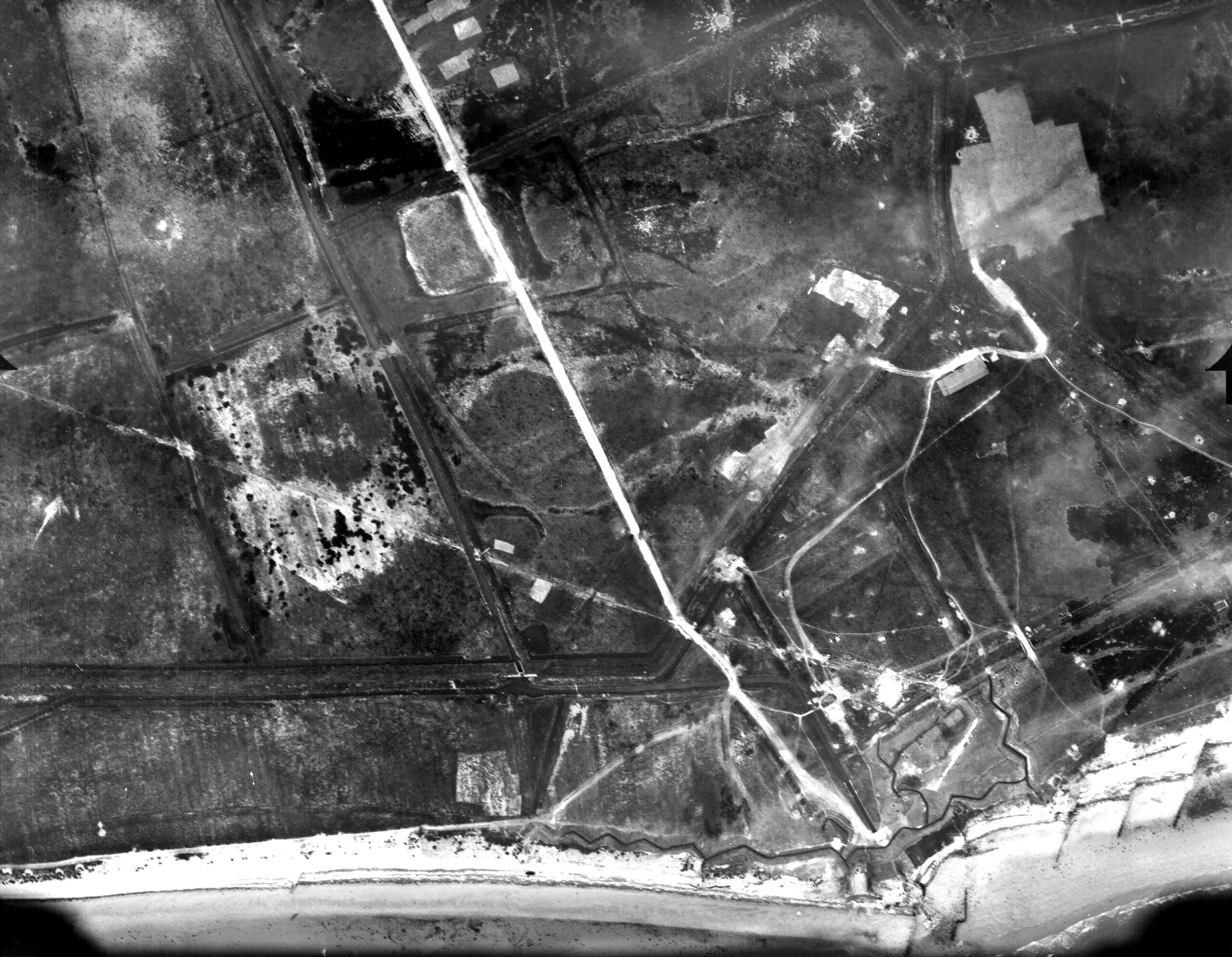 An aerial reconnaissance photograph of the coastal sector of Grandcamp-Maisy, France, taken on D-Day, June 6, 1944. Located west of Omaha Beach, this heavily fortified area contained key German artillery emplacements guarding the approaches to the Vire Estuary.