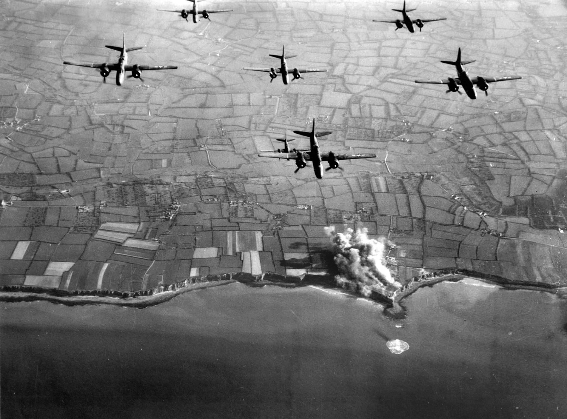Pointe du Hoc is shrouded in smoke and dust during an April 15, 1944 strike by Ninth Air Force A-20 Havoc medium bombers. Following heavy pre-invasion air raids like this, the Germans relocated their 155-mm guns to an orchard more than a mile inland.