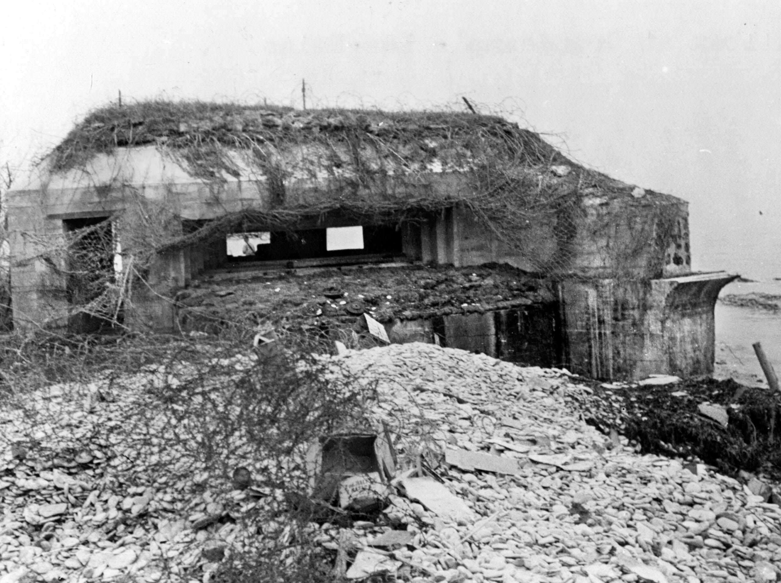 Located along the seawall near Grandcamp-Maisy harbor, Widerstandsnest 81 (“Resistance Nest 81”) served as a coastal observation post and defensive station for the main artillery batteries situated inland. Today, two concrete casemates and a ring-stand “Tobruk” bunker remain standing along the shore.