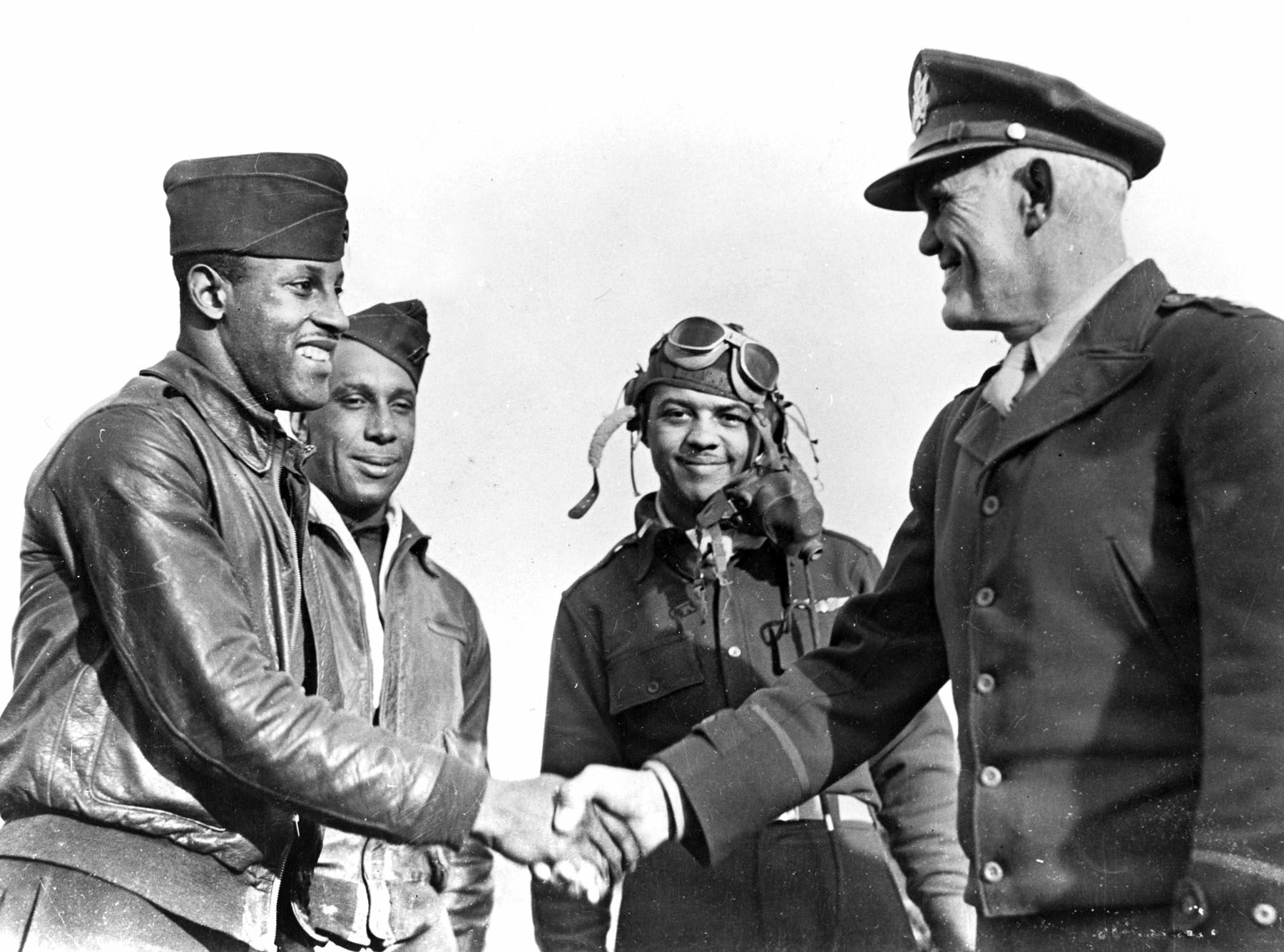 Major General John K. Cannon, commander of the Northwest African Tactical Air Force, congratulates Lt. Charles B. Hall on his landmark July 2, 1943 victory. Despite public commendations, Cannon and other senior Army Air Forces commanders later submitted reports alleging Black airmen lacked combat aggressiveness—claims disproven by the 332nd Fighter Group’s outstanding escort record.