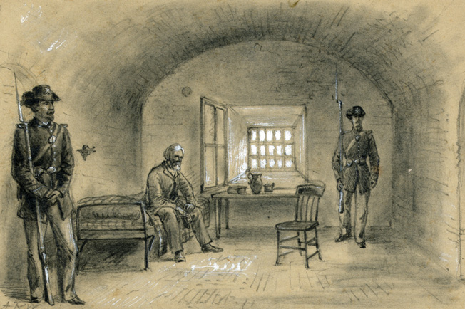 A weary and suddenly aged Jefferson Davis sits in chains under guard in his cell at Fort Monroe. He was released on bond two years later by President Andrew Johnson.