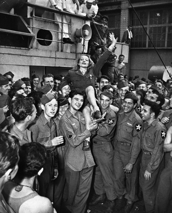 Marlene Dietrich is hoisted onto the shoulders of 2nd Infantry Division soldiers on the troopship SS Monticello as they return to New York Harbor at war’s end. General Patton once gave her a pistol for protection in the event she was ever captured by the Nazis.