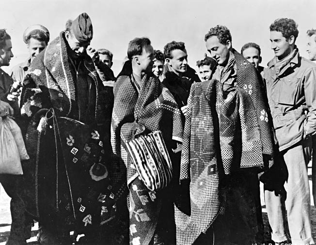 Crewmen from a downed aircraft of the Fifteenth Air Force escaped capture with the help of Yugoslav partisans. Here they arrive in Italy wearing Yugoslav blankets.