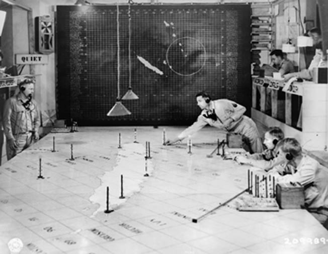 U.S. Army Signal Corps personnel track enemy and friendly aircraft movements via radio, radar, and a large map at an operations and early warning center located in Nouméa.
