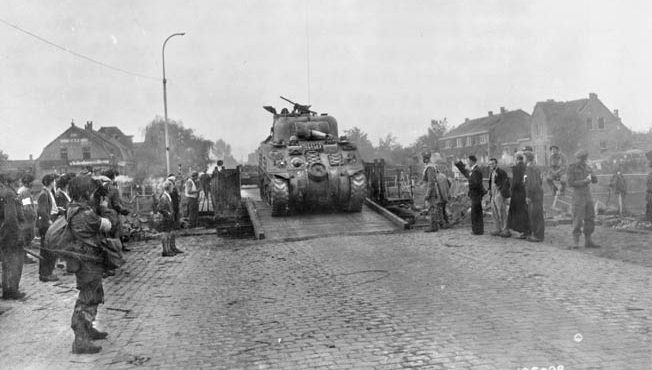 A British Sherman tank crosses the Wilhelmina Canal in Holland as American paratroopers of the 101st Airborne Division and Dutch civilians look on. Allied control of the Wilhelmina Canal was critical to the advance of ground forces toward British paratroopers at Arnhem.