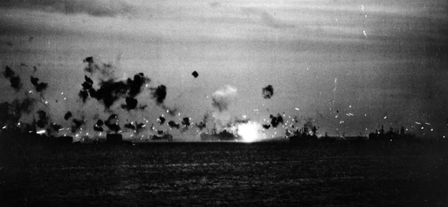 The evening sky is peppered with a flurry of antiaircraft bursts from the U.S. fleet off Kerama Retto, April 6, 1945. The bright flash may be a plane exploding on the water.
