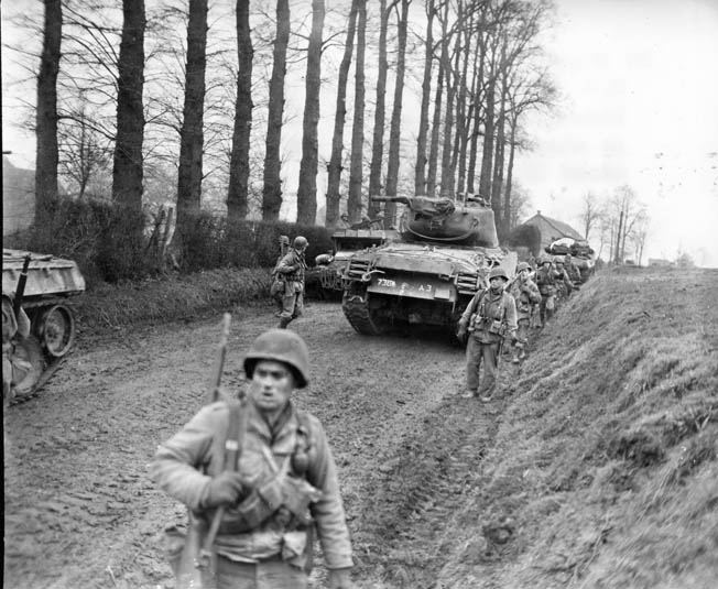 Infantrymen of the 83rd Division walk past Sherman tanks that have momentarily halted on a dirt road in Germany. This photo was taken in February 1945, and the war in Europe ended three months later.