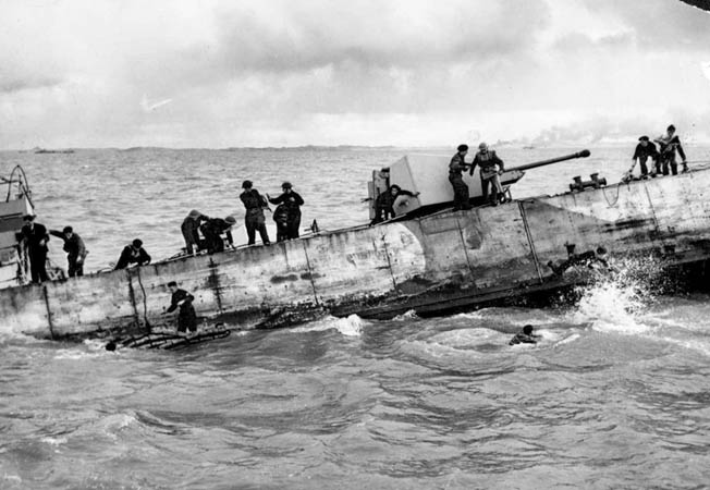 The crew of a Landing Craft, Gun (Medium) abandons ship after it was hit by German shore batteries during the landing of Royal Marines. 