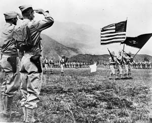 A color guard renders honors and accepts the salute of American officers, including General E.B. Sebree, during a review on New Caledonia. Sebree served as an assistant to General Alexander Patch, commander of U.S. forces on the island.