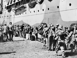En route to combat in the Solomon Islands, U.S. troops loaded with gear board a transport ship in the harbor at New Caledonia. The base at New Caledonia was vital to Allied ability to wage an offensive campaign in the South Pacific.