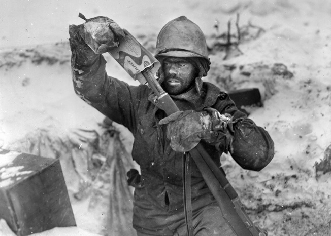 A soldier of the 99th Infantry Division covers the muzzle of his rifle during a lull in the fighting at Elsenborn Ridge. The remnants of the division were among the American troops that slowed the momentum of the German advance during the Battle of the Bulge, standing their ground in the face of the enemy onslaught. 