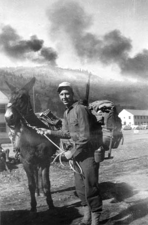 The author with his mule Elmer. The smoke in the background is from two D&RGW trains passing through the valley where Camp Hale, Colorado, was located.