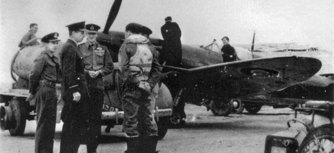 Chief Air Marshal Charles Portal, second from left, and Air Vice Marshal Keith Park, third from left, talk with fighter pilots while a Spitfire is fueled. 