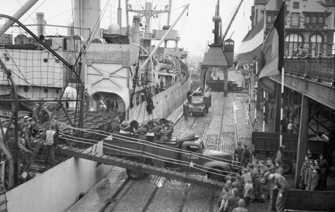 While the Antwerp port was taken in early September, it was not until late November that ships could unload. Here oil drums are offloaded from SS Fort Cataraqui, a British/Canadian variant of the American Liberty cargo ships, at Antwerp, November 30, 1944. This was the first ship to berth at the port following the long-delayed opening of the Scheldt Estuary.