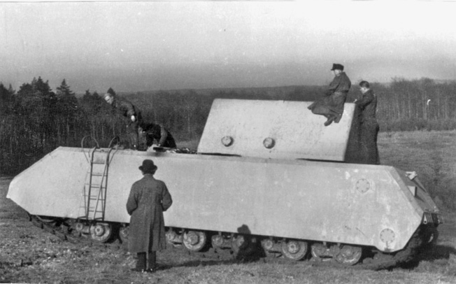 Engineers and dignitaries inspect the massive hulk of the Maus, an experimental tank of tremendous proportions. The concept of the Maus proved impractical, and only four prototypes were ever built.