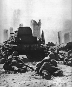 Japanese infantrymen crawl behind a tank through a shattered street during the Battle of Singapore, early February 1942.