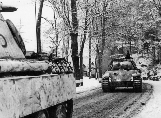 German PzKpfw. V Panther medium tanks roll along a muddy road silhouetted against a winter landscape during the early hours of the Ardennes Offensive. Walter's 3rd Platoon, Company L, 3rd Battalion, 393rd Infantry Regiment hunkered down for hours beside an unpaved road as German tanks and infantry streamed past.