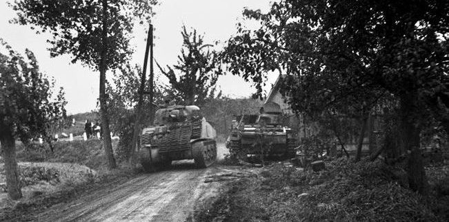A Sherman tank of the 47th/7th Dragoon Guards passes a knocked-out German PzKpfw III in Oosterhout near Nijmegen, September 27, 1944. Narrow roads such as this hampered Allied efforts to reinforce the heads of Nijmegen bridge. 