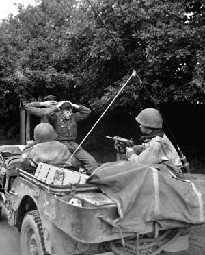 Two Germans surrender to 6th Armored Division troops during the American advance into Brittany. The soldier in the jeep is wielding a .45-caliber “grease gun” submachine gun. 