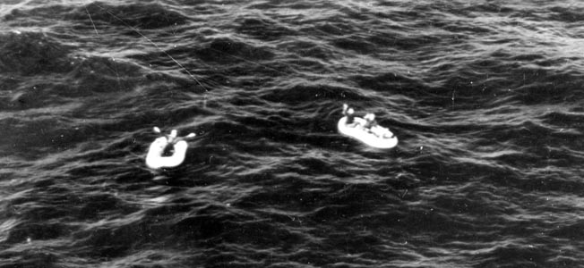 Three Allied crewmen, believed to be from a B-24 bomber piloted by Lieutenant Charles Moore, wave to rescue aircraft from their rafts in the open Atlantic. Their B-24 was shot down by a German Ju-88 over the Bay of Biscay.