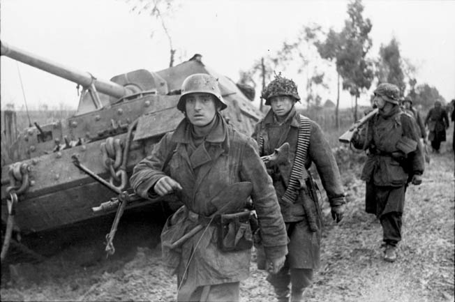 German soldiers advance past an abandoned armored vehicle during the bitter fighting around the Anzio beachhead in early 1944. The Allied amphibious landing at Anzio, south of Rome, was intended to initiate a lightning strike against the City of Light; however, the Americans failed to move with alacrity and Operation Shingle devolved into a bloody battle of attrition.