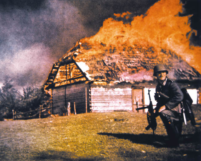 A structure fire with a WWII German soldier in the foreground. 