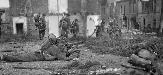 British assault troops advance through the rubble-strewn streets of Flushing.