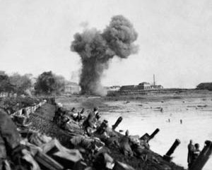 Artillery shells explode as British assault troops advance at dawn along the waterfront near Flushing, November 1, 1944. 