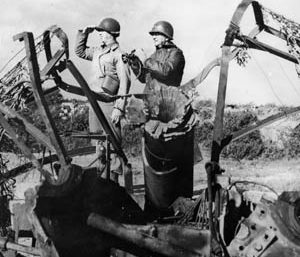 Brig. Gen. James A. Van Fleet, ADC of the 2nd Infantry Division, left, and Maj. Gen. Troy Middleton, VIII Corps commander, view battle from a destroyed German gun position. 