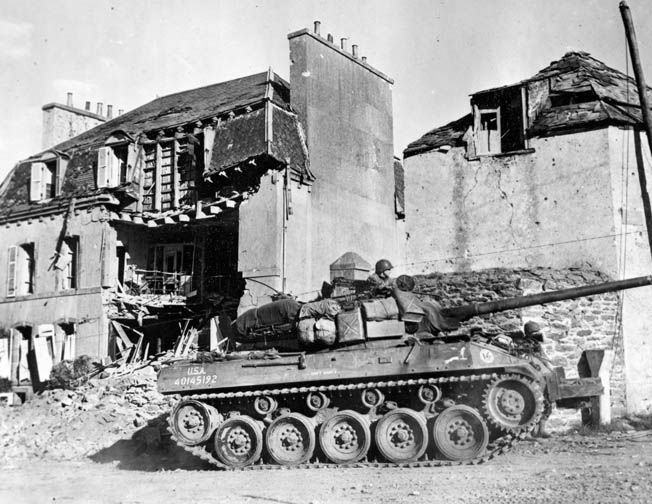 An American M-18 tank destroyer rolls through the shattered remains of a street in Brest.