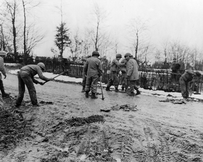 An American engineer unit digs up a roadway to plant antitank mines near St. Vith, Belgium. Both St. Vith and Bastogne were key German objectives.