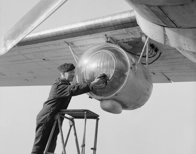 An excellent innovation deployed with sub-hunting aircraft that patrolled the Bay of Biscay, the Leigh Light was used to illuminate German U-boats on the surface and facilitate the speed of attacks. In this photo a Royal Air Force ground crewman cleans the plexiglass cover of a Leigh Light that has been installed under the wing of a Consolidated Liberator bomber. 