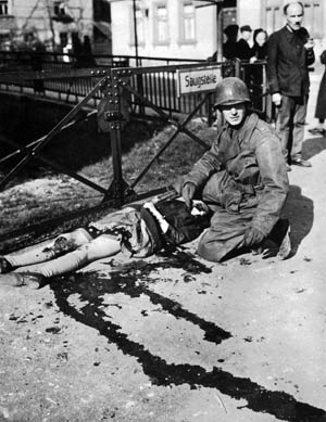 A lieutenant from Patton’s Third Army with the mangled body of a German girl accidentally killed when an Me-109 attacked American troops in the town of Muhlhausen.